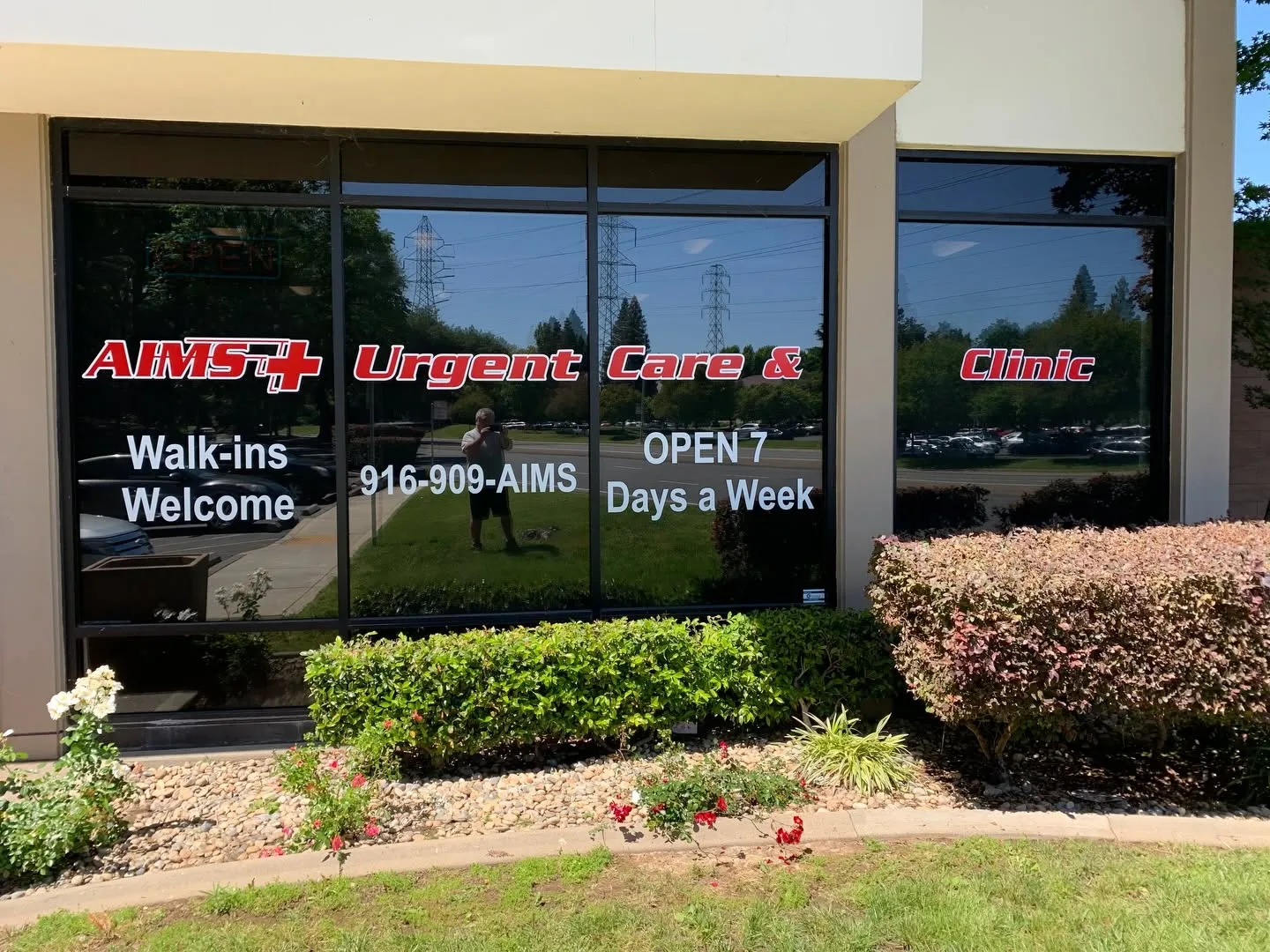 Installed window lettering job on the exterior of AIMS Urgent Care & Clinic, with red and white vinyl text across four large tinted windows